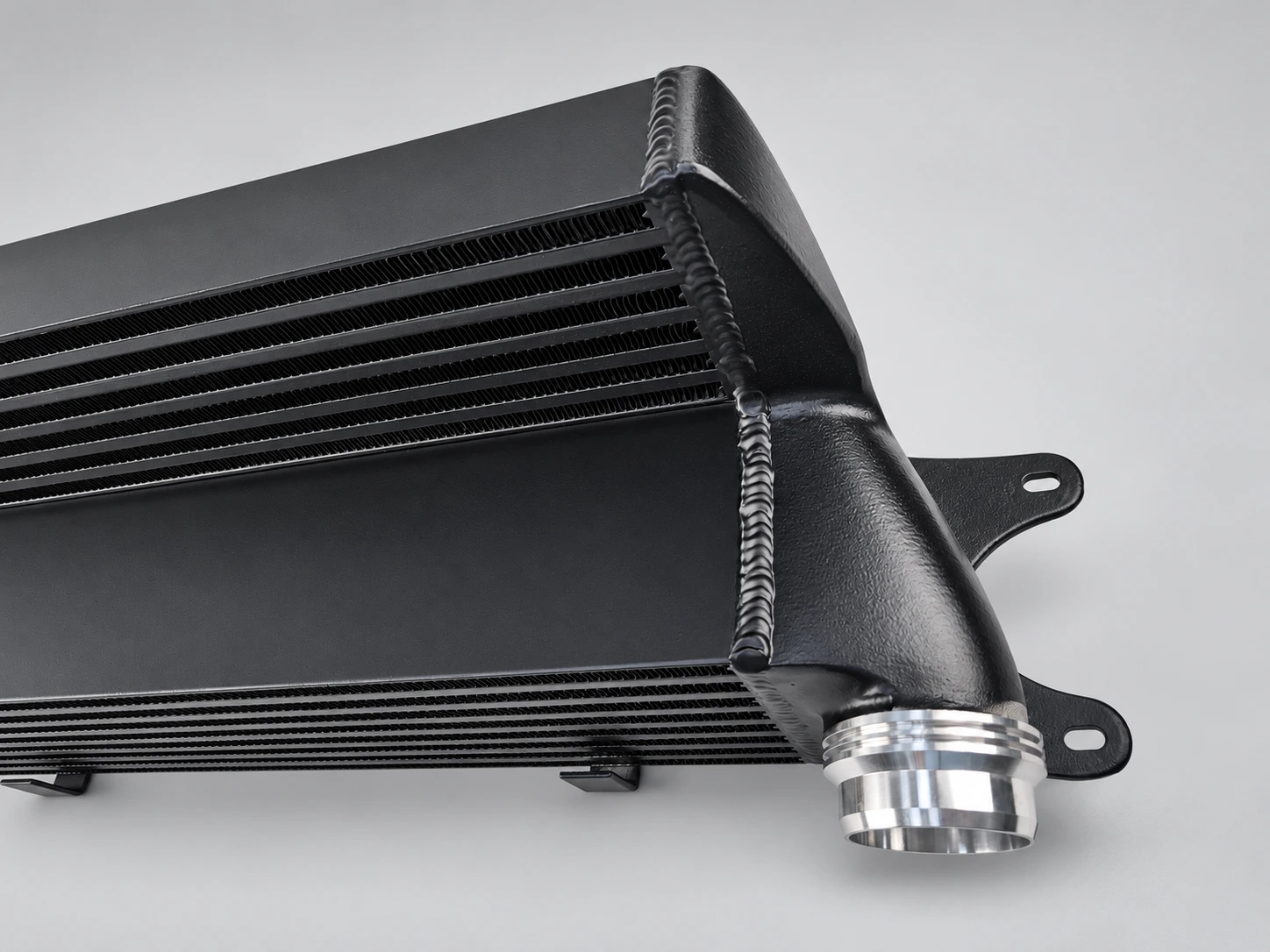 Black intercooler end tank with weld bead, mounting brackets and silver machined connection