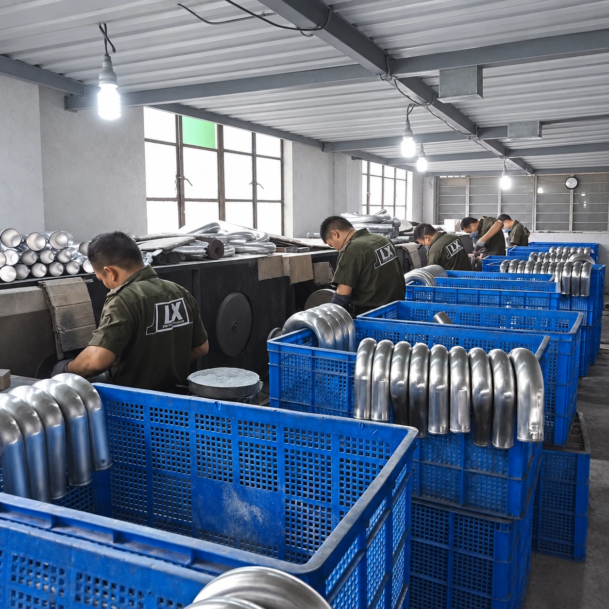 Workers grinding and polishing aluminum pipe bends.